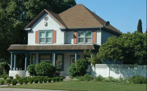 Two-story village house on a corner lot with a wrap-around porch.